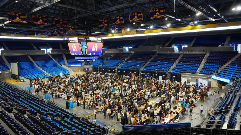 Wide view of the LA Hacks judging floor inside Pauley Pavilion, with teams gathered around tables for project judging.