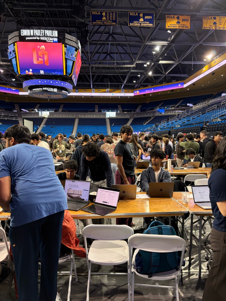 Teams at LA Hacks set up with laptops on judging tables inside Pauley Pavilion.