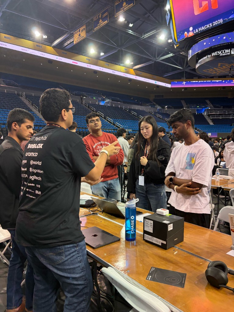 A LA Hacks team presenting a project at a judging table while a judge listens and asks questions.